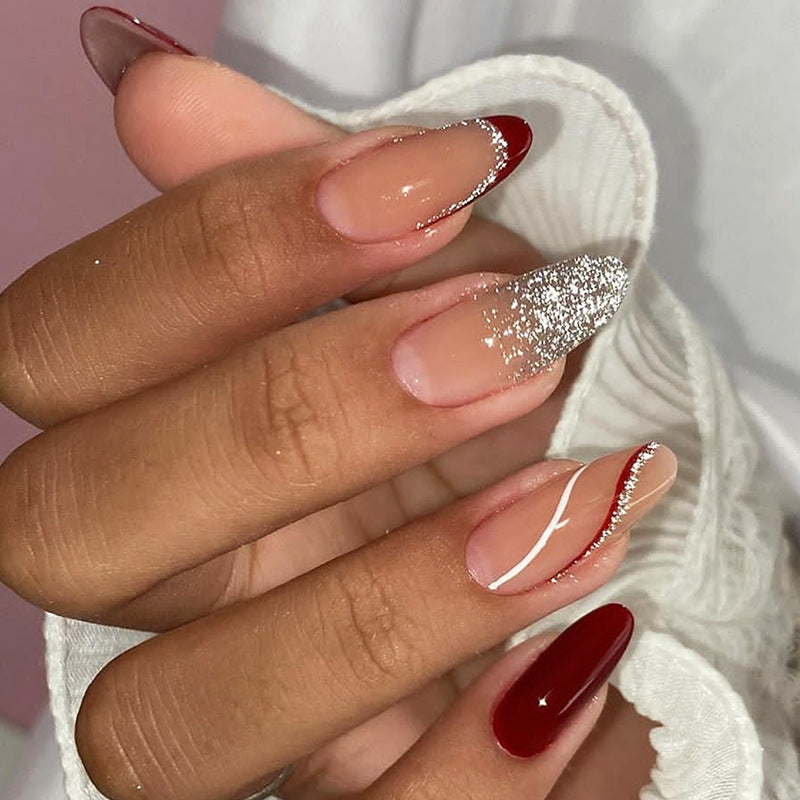 Close-up of a hand with red and silver glittery nail polish on a blurred background