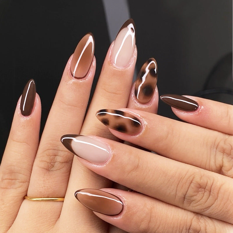 A set of press-on nails featuring a glossy brown finish with leopard print accents on the tips.