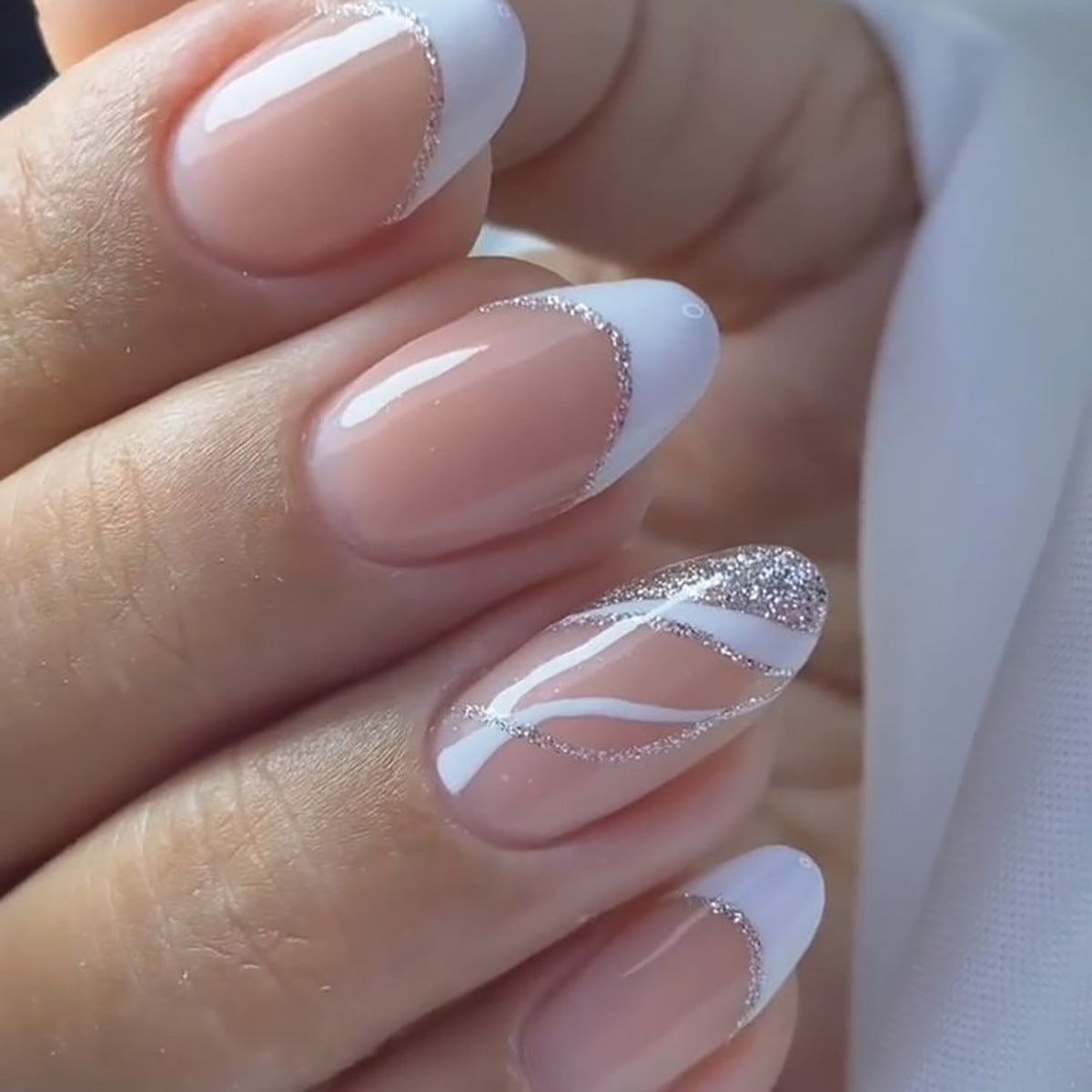 Close-up of a hand with white nail polish and silver glitter design.
