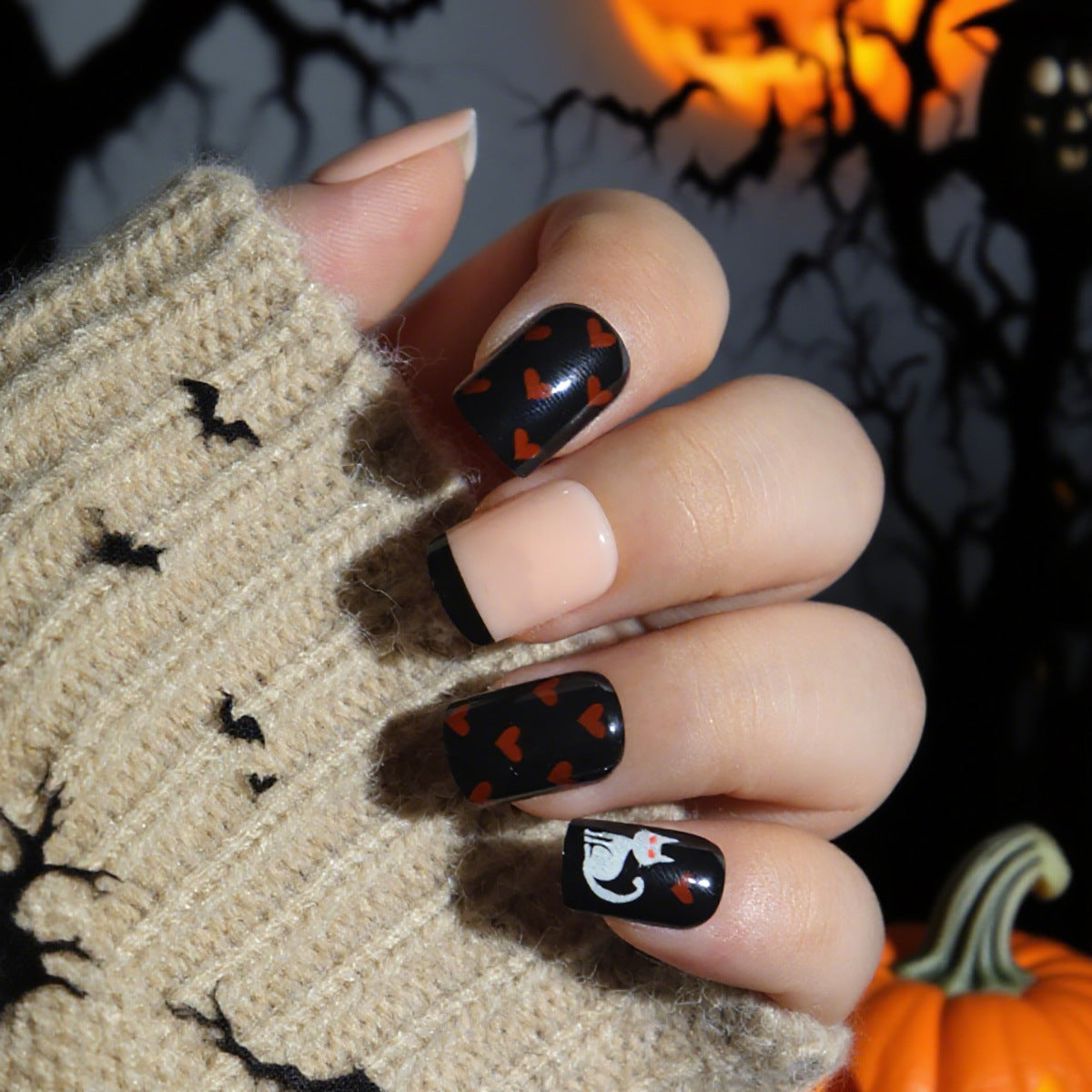 Halloween-themed nail art with black and orange design on a hand wearing a ghost glove.