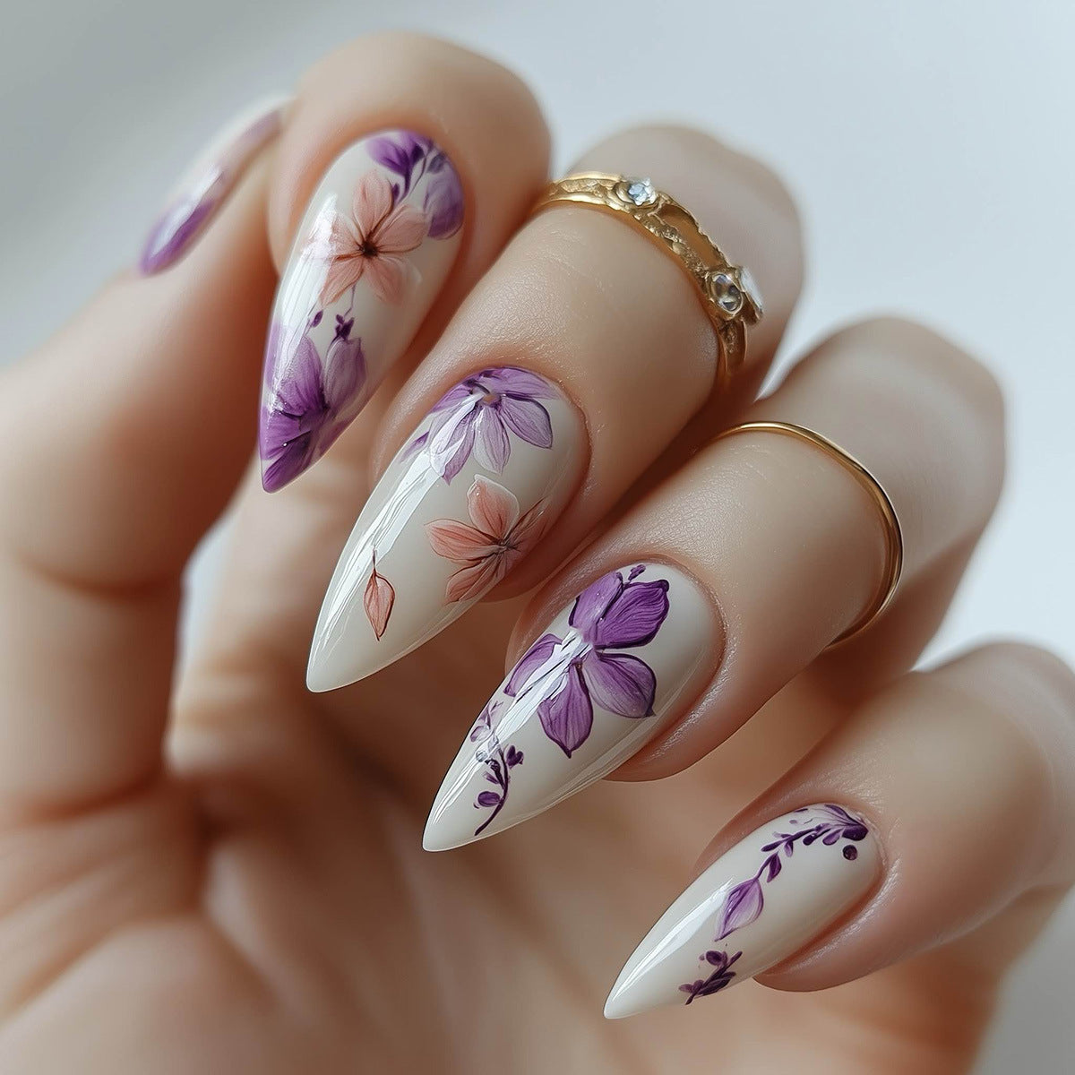 Nails with floral design and gold rings on a neutral background