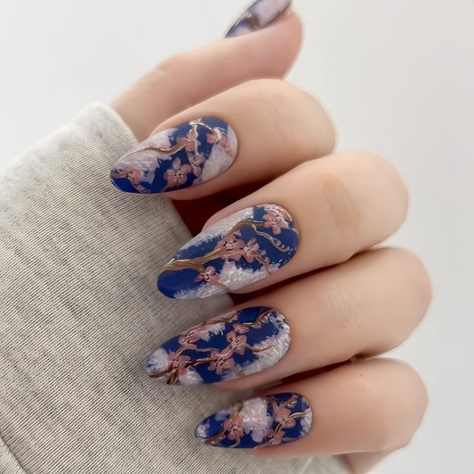 A set of acrylic press-on nails featuring a floral design with a combination of dark blue and lighter pastel flowers.