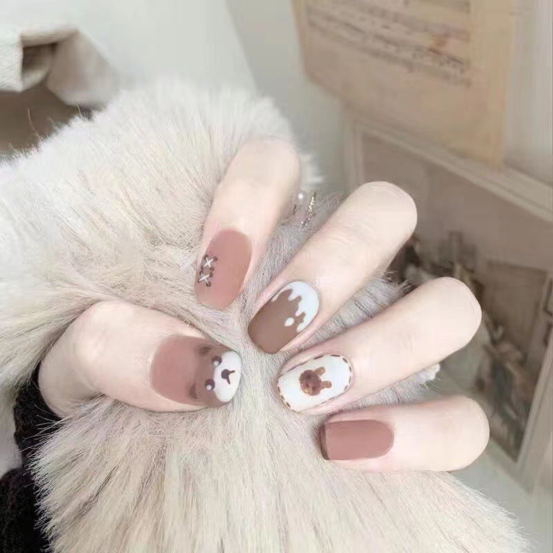 Close-up of hands with brown nail polish and animal print design, wearing a fluffy white garment.