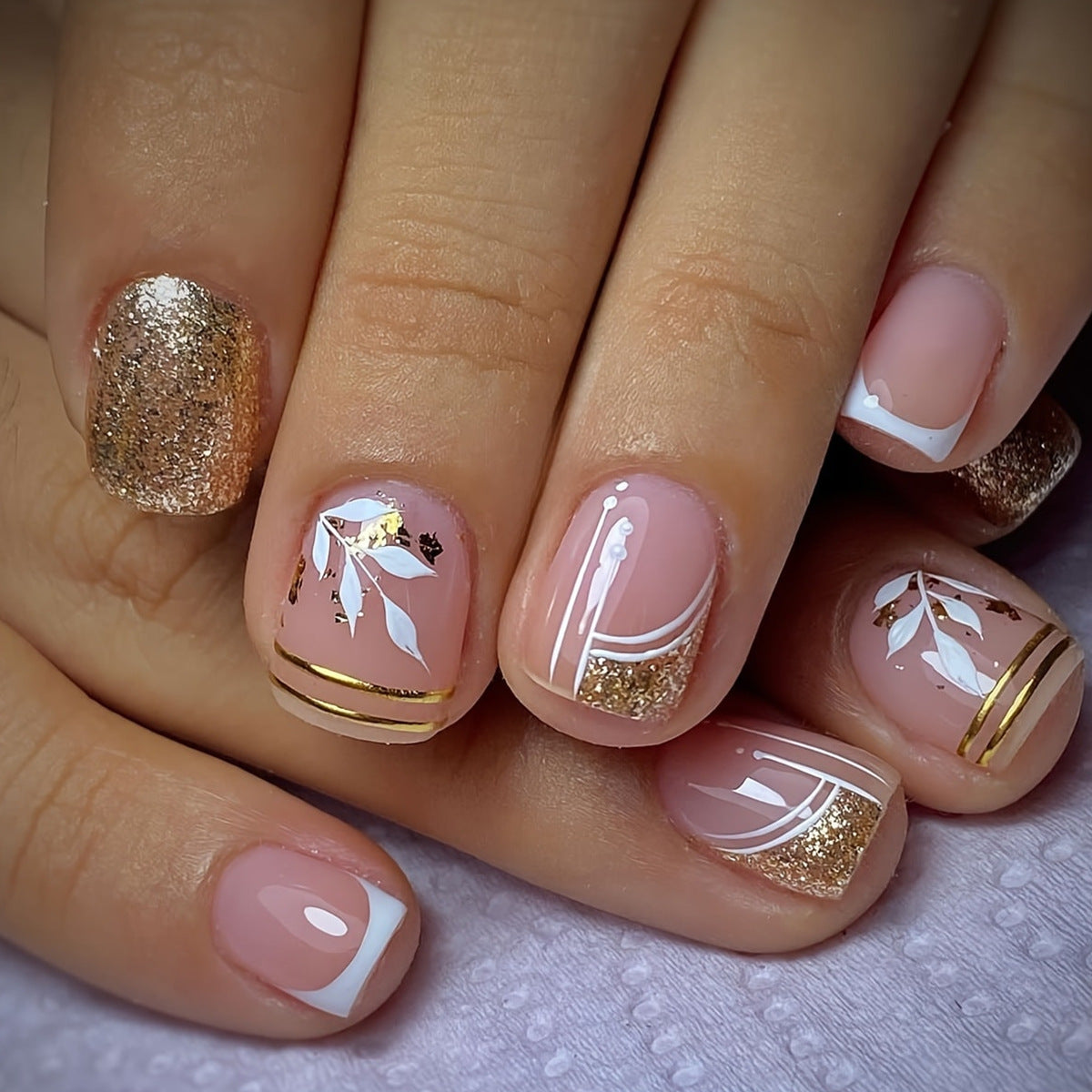 Nails with gold and white designs on a light background
