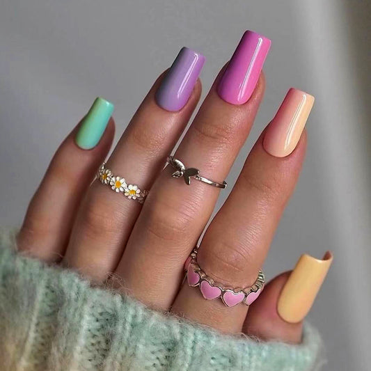 Hand with pastel nail colors and multiple rings on a neutral background