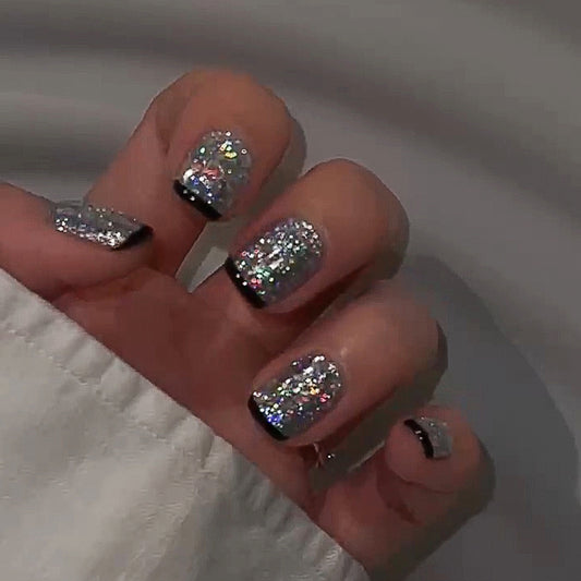 Close-up of a hand with glittery nail polish on a neutral background