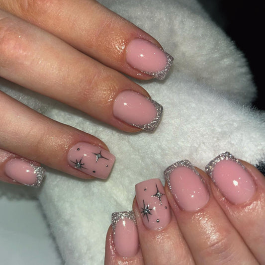 Close-up of hands with pink nails and star designs on a white background