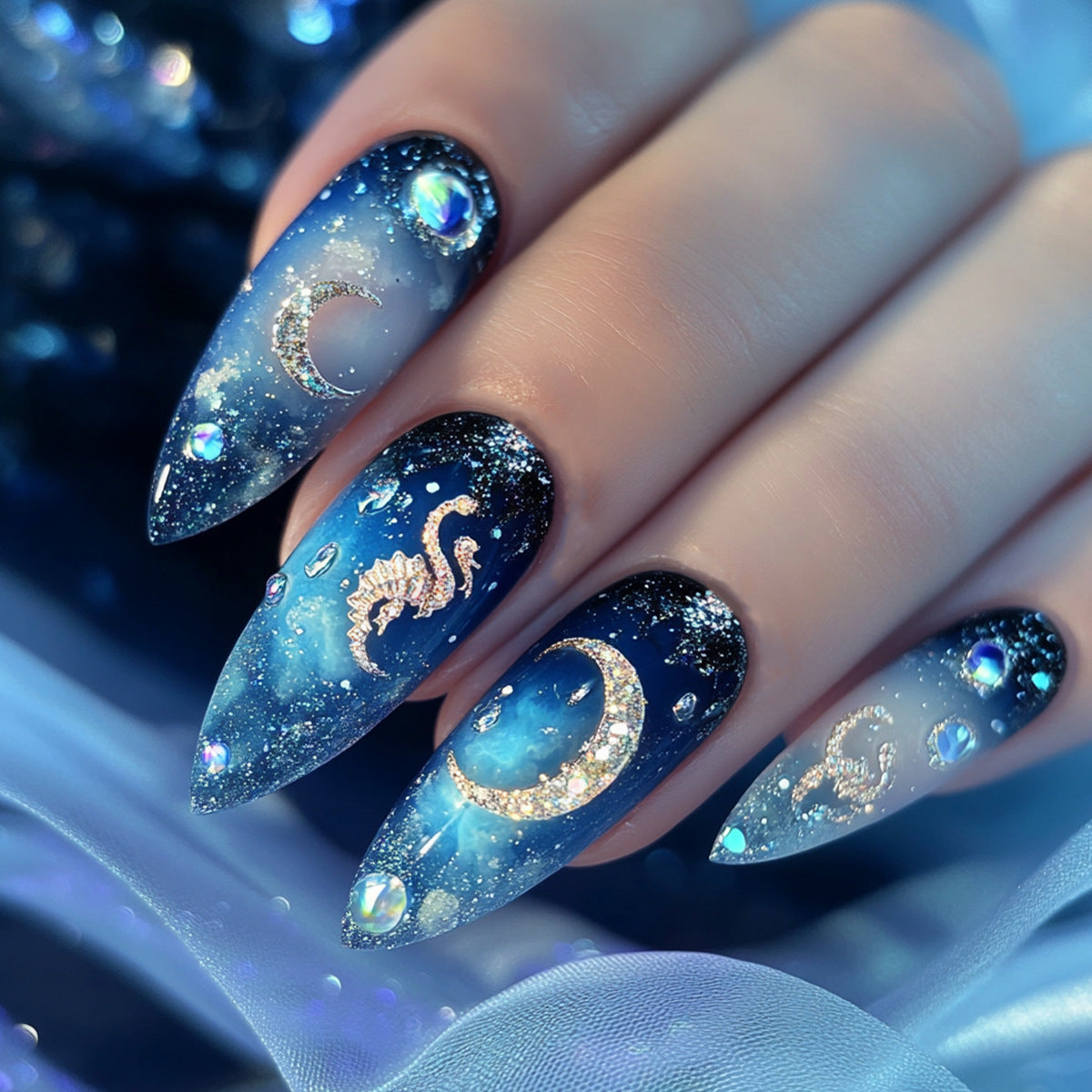 Nails with blue and black design featuring moons and stars on a blurred background.