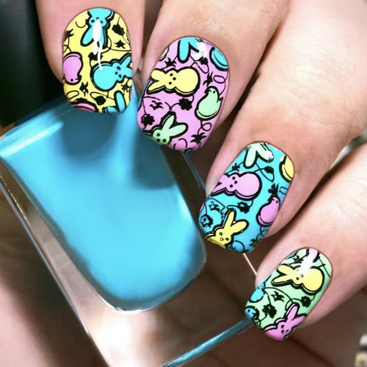 Nails with colorful cartoon-themed design held above a blue nail polish bottle.