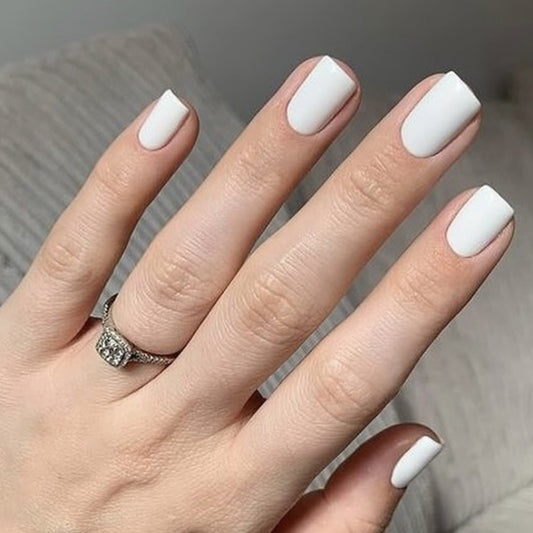 A set of short square white press-on nails with a matte finish, displayed on a person's hands.