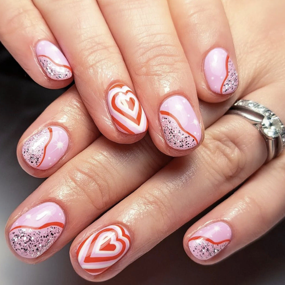 Nails with pink and white heart designs on a neutral background
