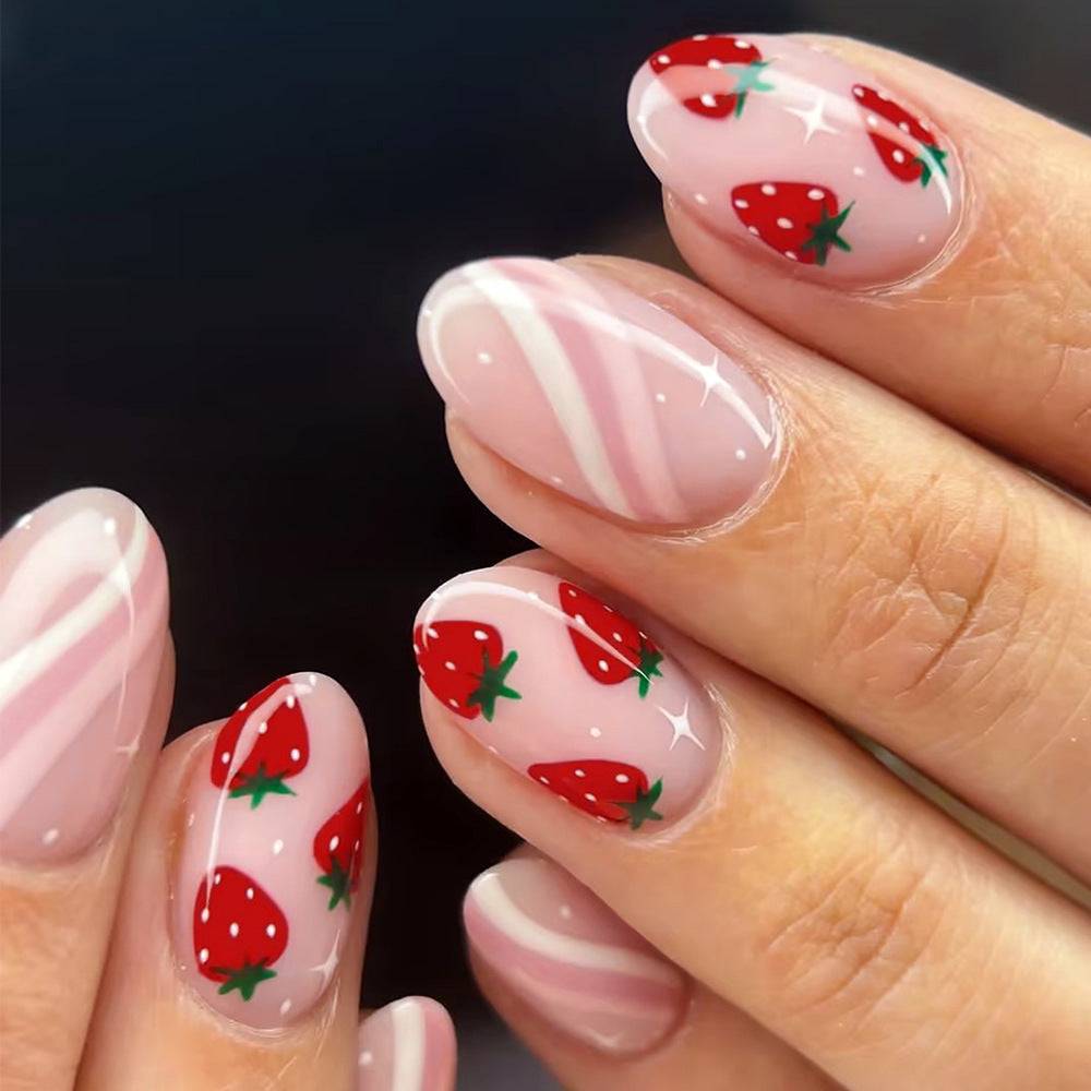 A set of almond-shaped nails with a pink base and strawberry designs in red and green colors, including a shiny finish.