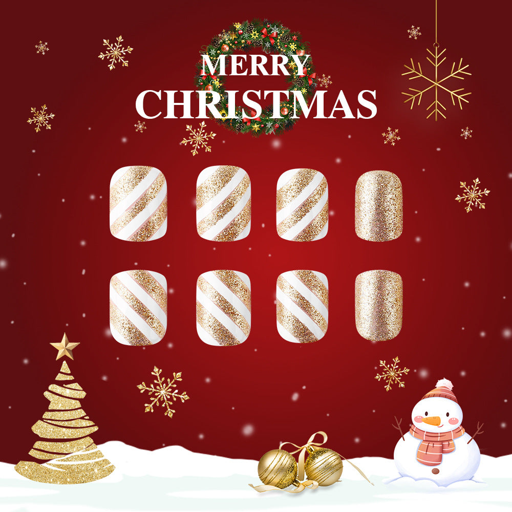 A set of press-on nails with white and gold glitter, featuring medium-sized square shapes with striking white stripes, displayed against a Christmas-themed background with a Merry Christmas message, snowflakes, and a Christmas tree.