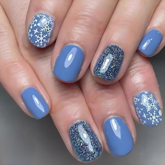 Close-up of hands with blue nail polish and snowflake designs on a neutral background