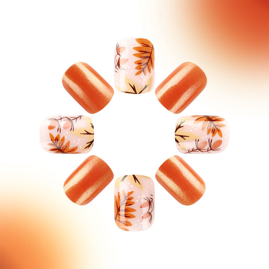 A set of press-on nails with a floral design, featuring orange and beige colors with gold accents.