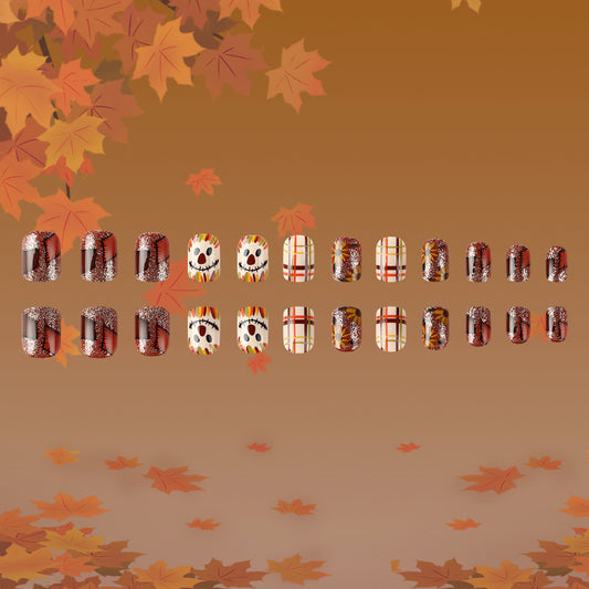 A collection of press-on nails with various autumn-themed designs, including leaves and scarecrows, displayed in square shape on a brown background with fallen leaves around.