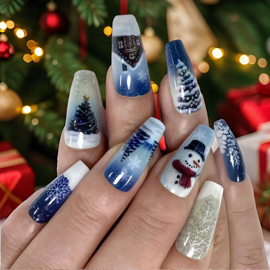 A set of long coffin-shaped nails with a winter wonderland design featuring a snowman, Christmas tree, and snowflakes in shades of blue and white.