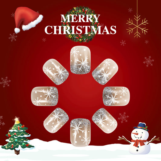 A set of press-on nails featuring a Christmas theme with a red background, white snowflake designs, and clear glitter accents, displayed alongside a Christmas tree and a snowman.