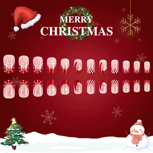 A set of red and clear press-on nails with Christmas-themed designs, including snowflakes and holiday motifs, displayed against a festive Christmas background.