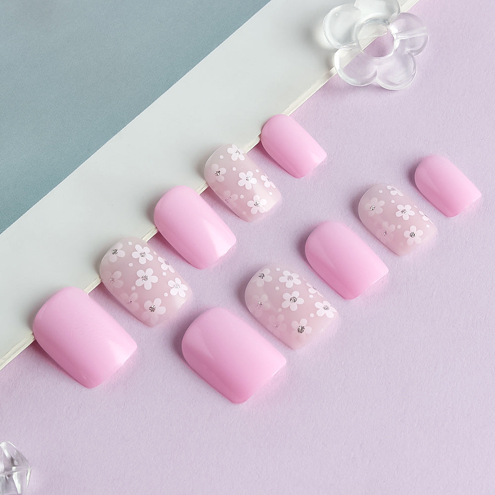 Pink nail art with floral designs on a light purple background