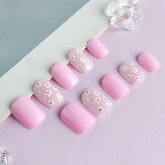 Pink nail art with floral designs on a light purple background