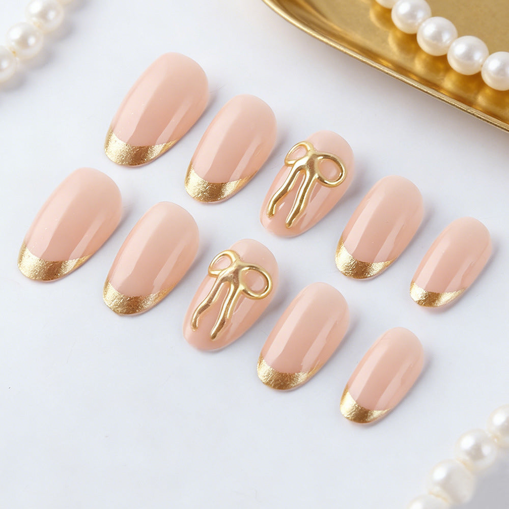Elegant Serenity Short Almond Pink Nails with Gold Accent Detail and Unique Bow Design Set