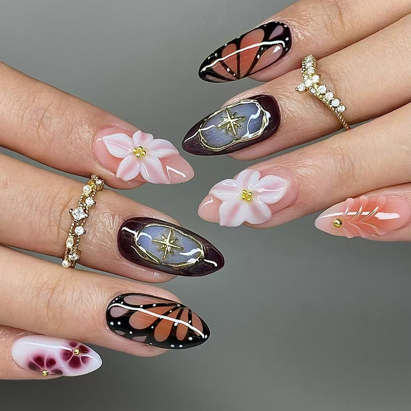 Nails with artistic designs including flowers, butterflies, and abstract patterns on a gray background.