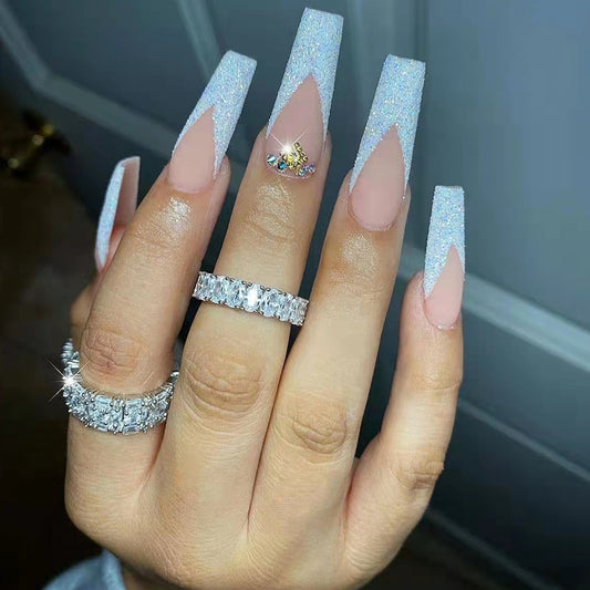 Hand with long, glittery nails and multiple diamond rings on a neutral background