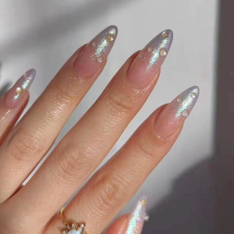 A hand with iridescent, multicolor glittery nails with shimmer accents, wearing press-on nails.