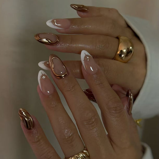 A set of almond-shaped press-on nails with a glossy white finish and metallic accents, displayed on a person's hands.
