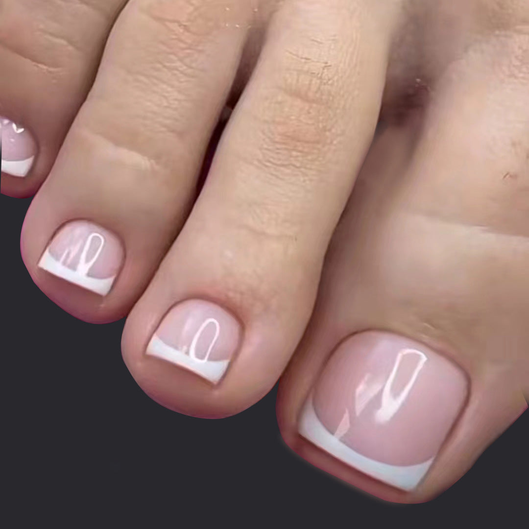 Close-up of toes with pink nail polish and white accents on a dark background