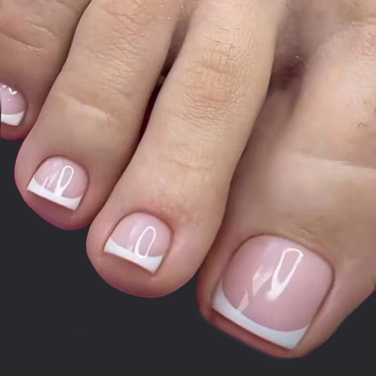 Close-up of toes with pink nail polish and white accents on a dark background