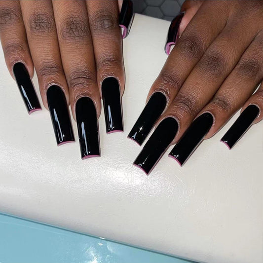 A pair of long square black glossy press-on nails displayed on a mannequin hands.