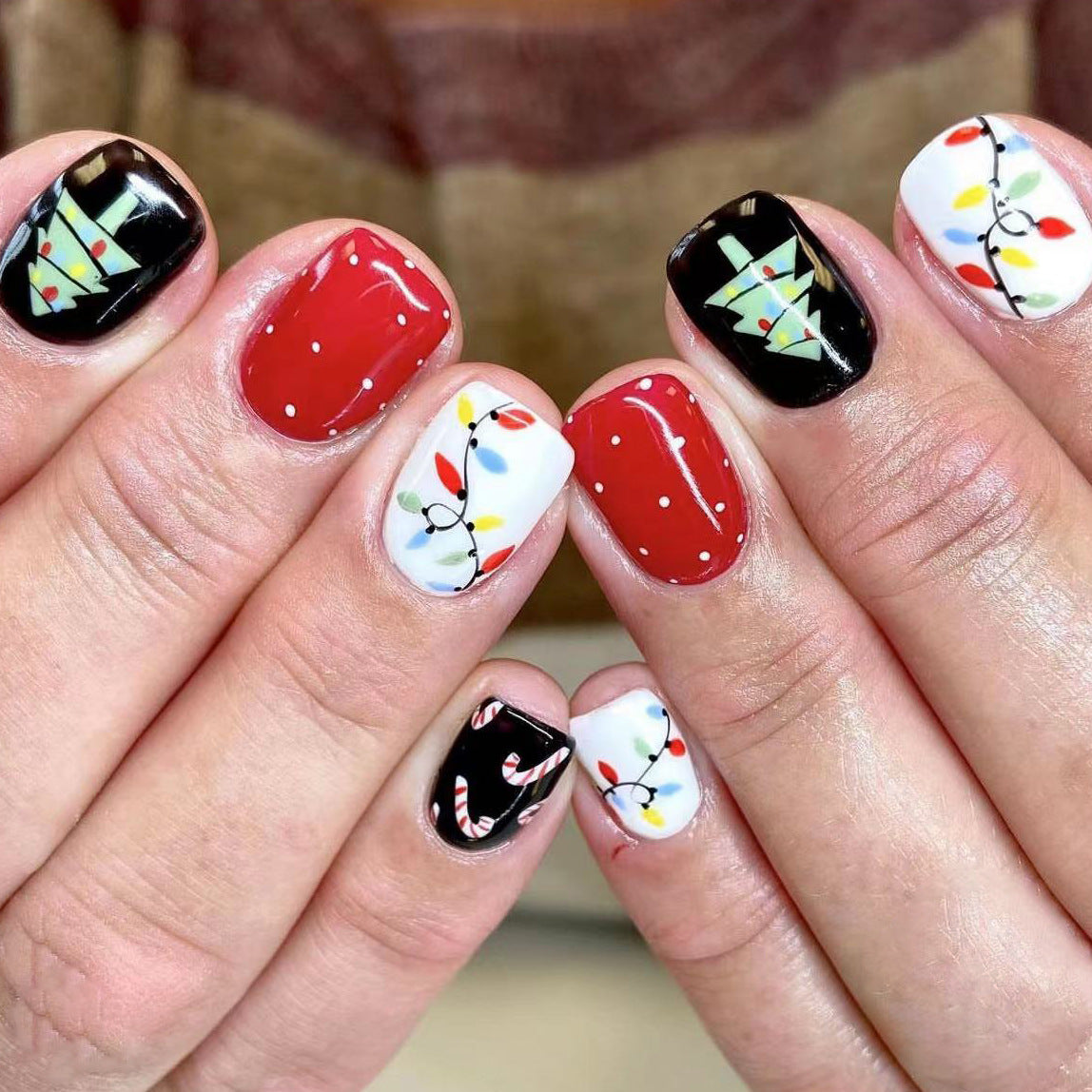 A set of press-on nails featuring various Christmas-themed designs including red, black, and white colors with candy cane and Christmas light patterns.