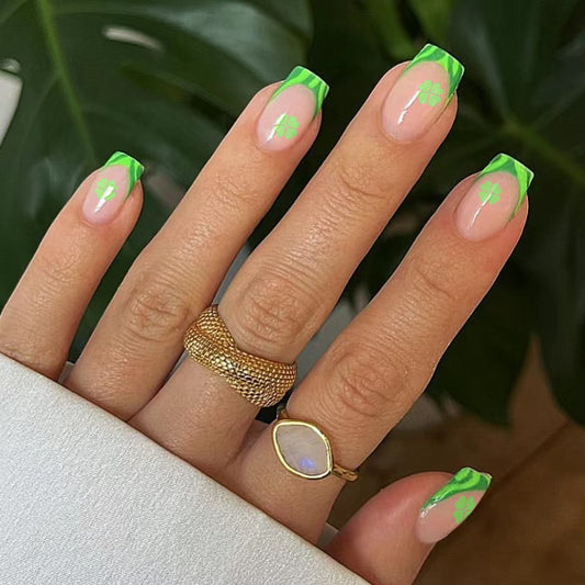 A medium set of square-shaped press-on nails featuring a neon green French tip design with clover accents on the free edge.
