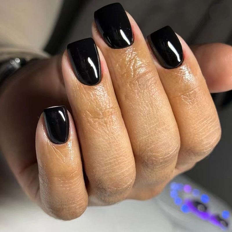 Hand with black nail polish on a neutral background