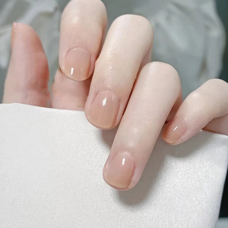 Close-up of a hand with nude-colored nail polish on a white background