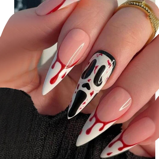 A hand showcasing press-on nails designed with a long stiletto shape, featuring black and white designs with red drip accents, indicative of a Halloween motif.