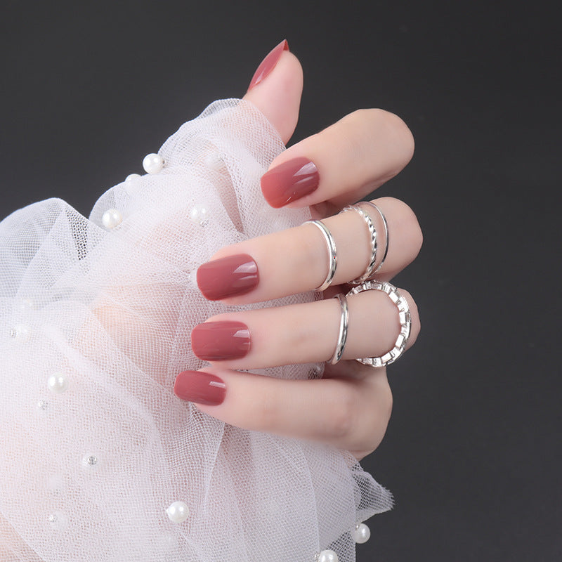Hand with red nail polish wearing silver rings on a dark background