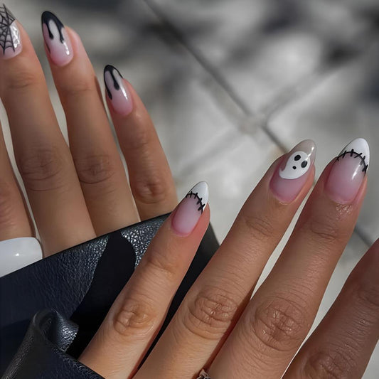 A hand with press-on nails featuring a medium almond white design with black tips and decorative elements suitable for Halloween.