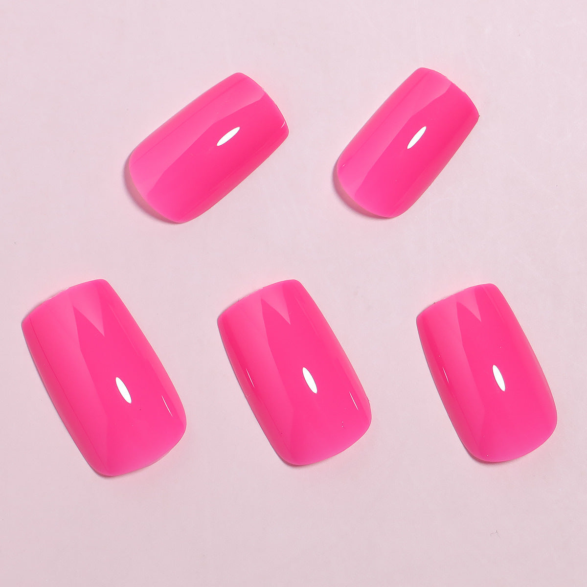 A set of hot pink glossy press-on nails displayed on a pink background.
