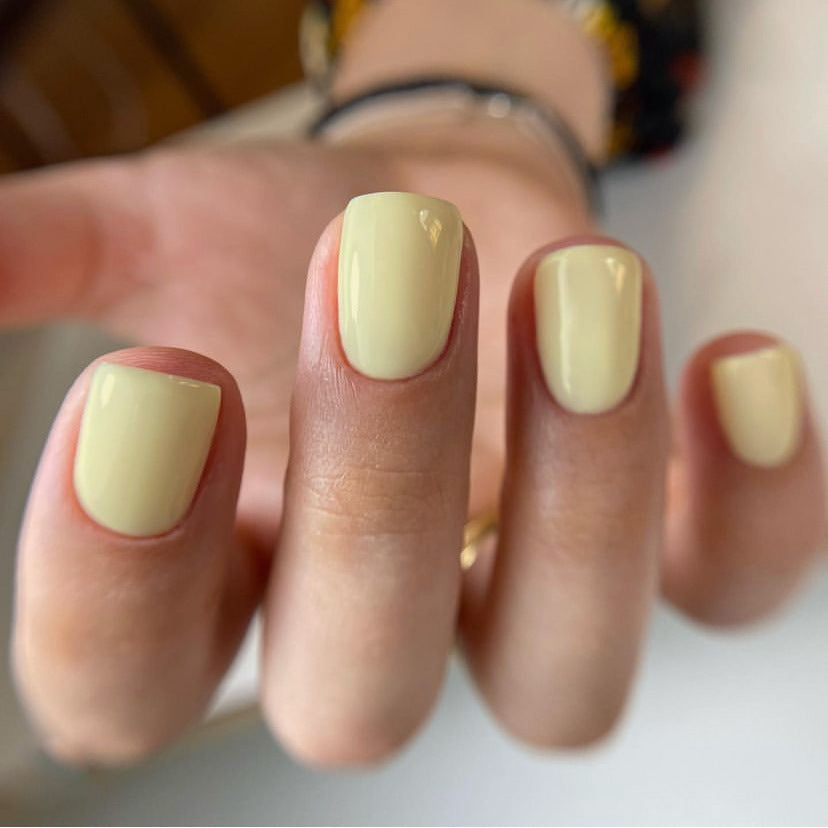 A hand with ivory-colored press-on nails with a natural gloss finish.