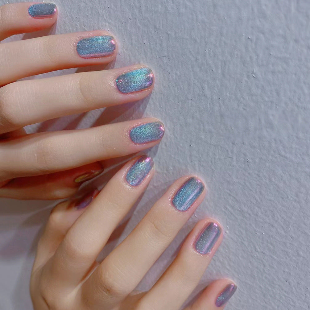 A pair of hands displaying press-on nails with a medium squoval shape and a strong blue glitter finish.