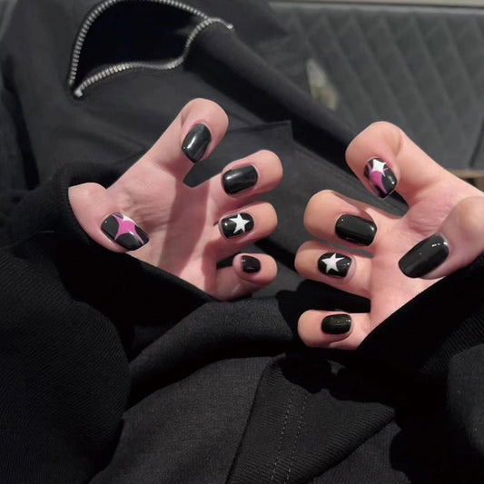 Close-up of hands with black and pink nail designs against a dark background