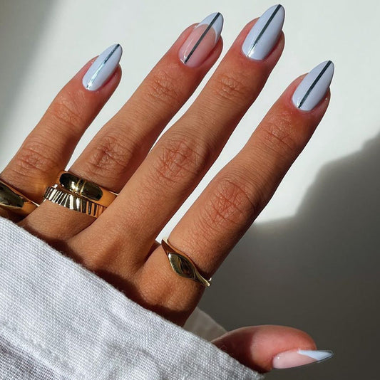 A set of medium-sized, almond white false nails with a black accent line design, worn on a person's hands.