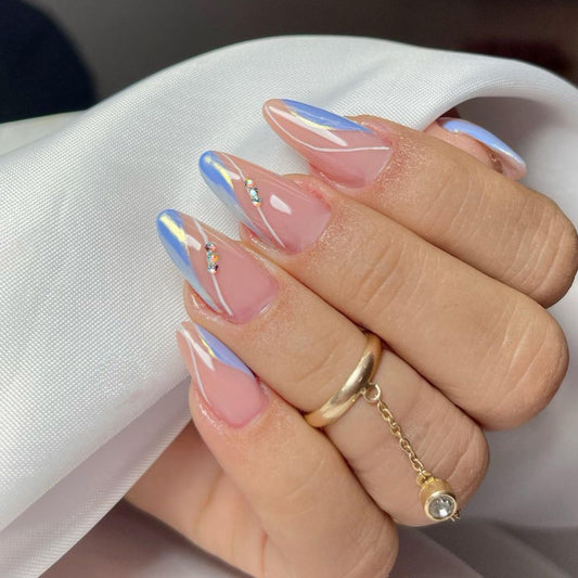 Hand with pink and blue gradient nails wearing a gold ring on a white background