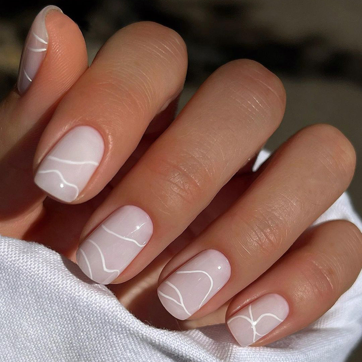 A pair of medium-sized, white, grooved, press-on nails.