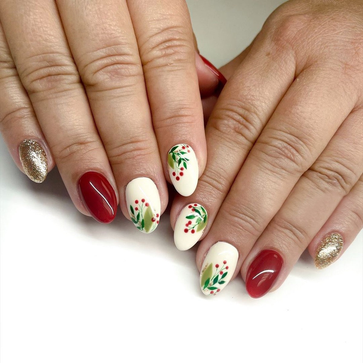 A set of press-on nails featuring a design with holly and berries in red, white, and green colors.