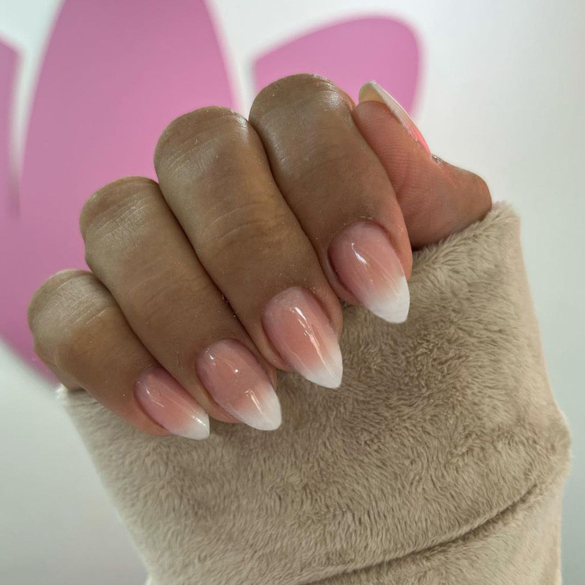 Close-up of a hand with pink nail polish on a white background