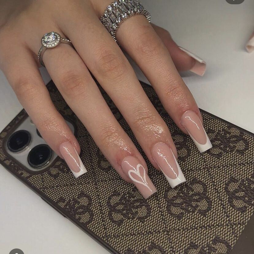 Hand with long, almond-shaped nails featuring a heart design on a patterned surface.